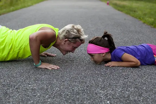 50 year old woman doing pushups with grand daughter 